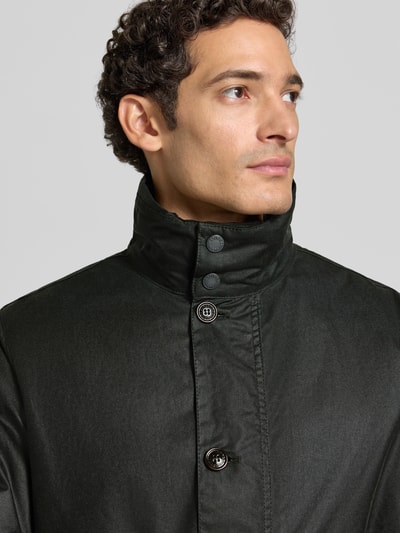 Männermodel trägt Regular Fit Parka aus reiner Baumwolle von Barbour in dunklem Grün, dezente Knöpfe, glatte Textur, Nahaufnahme Oberkörper.
