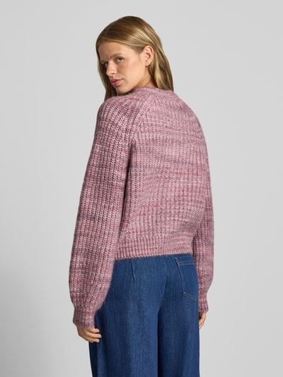 Frauenmodel trägt Cardigan mit Woll-Anteil und Rundhalsausschnitt von REVIEW in Rosatönen, grob gestrickt, gerader Schnitt, Rückenansicht, Material-Mix mit Woll-Anteil, Ganzkörperansicht Rückansicht.