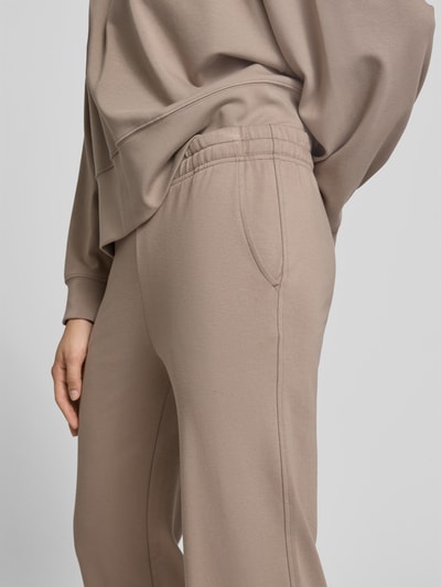 Vrouwenmodel draagt Flared Fit Sweatpants met Tunnelkoord van Juvia in mix van katoen en modal met Steekzakken, detailopname heup