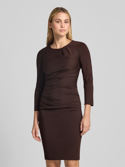 Frauenmodel trägt Cocktailkleid mit Raffungen von Rinascimento in Braun, Rundhalsausschnitt, knielang, Langarm, Material-Mix, Nahaufnahme Oberkörper.