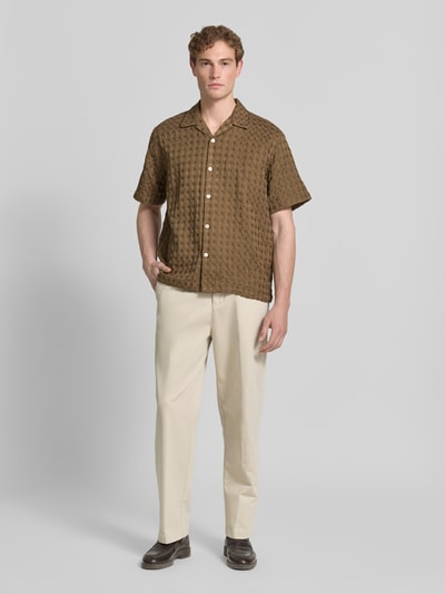 Męski model ma na sobie Relaxed Fit Freizeithemd aus reiner Baumwolle Modell 'MONTY' od SELECTED HOMME, brązowa krata, krótki rękaw, materiał jacquard, widok całej sylwetki z przodu.