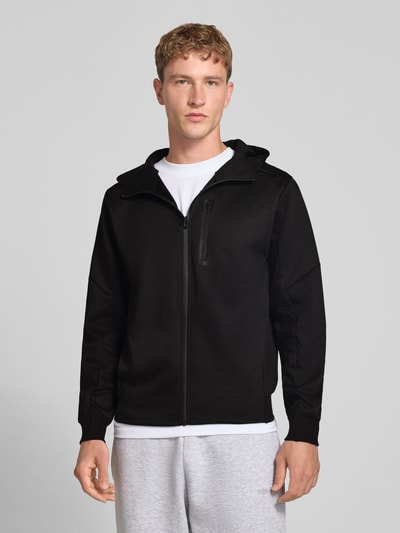 Männermodel trägt schwarze Sweatjacke mit Reißverschluss Modell 'COFUSION' von JACK & JONES, lockerer Schnitt, Material-Mix, Ganzkörperansicht von vorne.