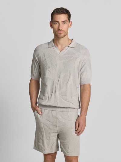 Männermodel trägt Relaxed Fit Poloshirt aus reiner Baumwolle Modell 'ASURFO' von BOSS Orange, Optik: Unifarben, Struktur, Label-Applikation, Polokragen, V-Ausschnitt, Kurzarm, Rumpfabschluss und Ärmelabschluss gerippt, Materialverarbeitung: Frottee, Farbe Beige, Ganzkörperansicht von vorne.