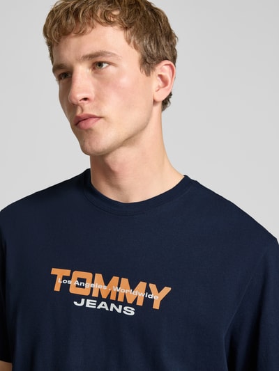 Männermodel trägt Regular Fit T-Shirt aus reiner Baumwolle von Tommy Jeans in Optik: Unifarben mit Label-Schriftzug, Nahaufnahme Oberkörper.