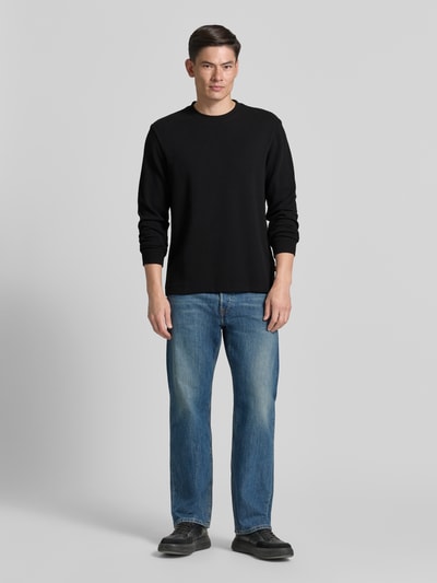 Mannelijk model draagt Regular Fit Langarmshirt aus Baumwoll-Mix Modell 'WE-TEMPEST' van BOSS Orange, zwart, uni, labelpatch, ribgebreide manchetten, fijnribstructuur, ronde hals, lange mouw, volledige lichaamsvoorzijde.