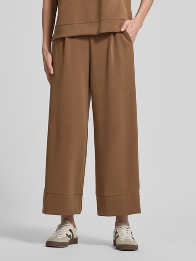 Männermodel trägt Sweatpants mit elastischem Bund von Rich & Royal, modalowa mieszanka, krój wide fit, kieszenie z tyłu, długość nogawki 66 cm, kolor brązowy, gładka tekstura. Nahaufnahme dolnej części ciała.