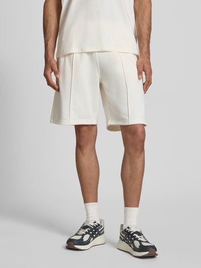 Männermodel trägt Bermudas mit elastischem Bund und Label-Stitching von CHAMPION, Baumwoll-Mix, Regular Fit, Längsnähte, Ganzkörperansicht von vorne.