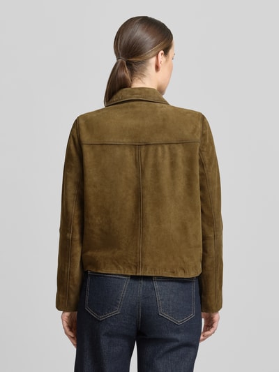 Vrouwenmodel draagt Lederblazer mit aufgesetzten Eingrifftaschen van Stefanel in olijfgroen echt leer, recht model, reverskraag, knoopsluiting, ruglengte maat S 52 cm, borstwijdte maat S 48 cm, mouwlengte maat S 59 cm, opgestikte steekzakken, rugaanzicht, Ganzkörperansicht Rückansicht.