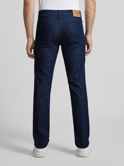 Męski model nosi Modern Fit Jeans mit Eingrifftaschen Modell 'Mitch' od JOOP! Jeans, bawełniany materiał z domieszką stretchu, krój modern fit, granatowy kolor, widoczne detale labelu, szerokość w rozmiarze 32/32: 44 cm, długość nogawki: 82 cm, całkowity widok z tyłu.