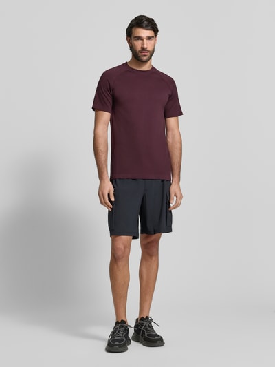 Männermodel trägt Fabletics Slim Fit T-Shirt mit Logo-Print Modell 'Training Day' in Dunkelrot, Rundhalsausschnitt, Herren T-Shirt, Ganzkörperansicht von vorne. Rückenlänge bei Größe M: 71 cm.