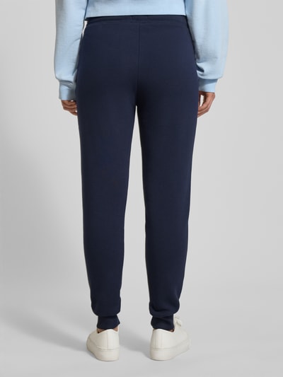 Frauenmodel trägt Sweatpants mit elastischem Bund von Christian Berg Woman aus dunkelblauem Baumwoll-Mix, Lockerer-Schnitt, Ganzkörperansicht Rückansicht.