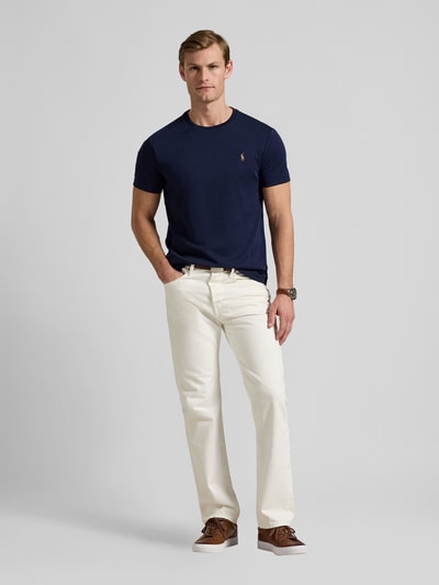 Męski model nosi Slim Fit T-Shirt aus reiner Baumwolle von Polo Ralph Lauren, granatowy kolor, logo, krótki rękaw, krój slim fit, widok całej sylwetki z przodu