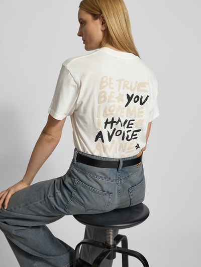 Frauenmodel trägt T-Shirt mit Label-Print von Anine Bing in Weiß, Reine Baumwolle, Lockerer-Schnitt, Rückenlänge 70 cm, Ganzkörperansicht Rückansicht.
