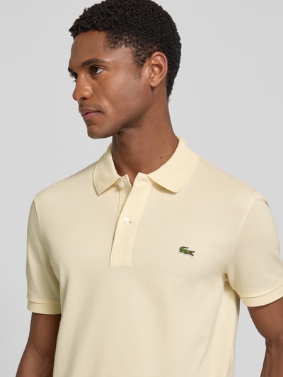Männermodel trägt Slim Fit Poloshirt aus reiner Baumwolle von Lacoste in Hellgelb, kurze Ärmel, Herren Poloshirt, Nahaufnahme Oberkörper.