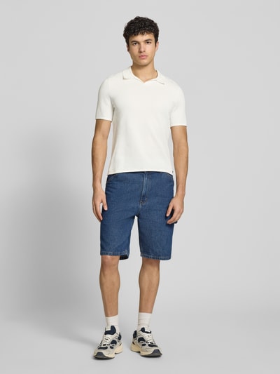 Männermodel trägt Slim Fit Poloshirt mit Strukturmuster von REVIEW in Creme, reine Baumwolle, kombiniert mit Jeansshorts, Ganzkörperansicht von vorne.