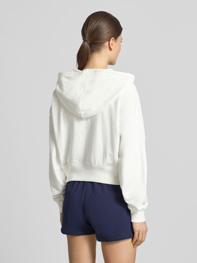 Vrouwenmodel draagt Regular Fit sweatjack met logo-stitching model 'Heritage' van GAP in katoenmix, capuchon, kangoeroezak, elastische boorden. Ganzebody achteraanzicht.