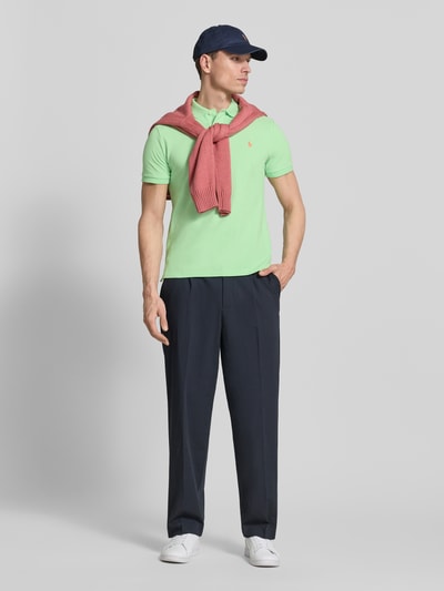 Männermodel trägt Regular Fit Poloshirt aus reiner Baumwolle von Polo Ralph Lauren in Hellgrün mit Logo-Detail, Ganzkörperansicht von vorne.