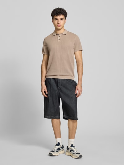 Męski model nosi Modern Fit Poloshirt mit kurzer Knopfleiste Modell 'JESS' od Jack & Jones, bawełniana mieszanka, półprzezroczysty design, kołnierzyk polo, krótka listwa guzikowa, długość pleców w rozmiarze M: 68 cm, beżowo-czarny, tekstura prążkowana, widok całej sylwetki z przodu.