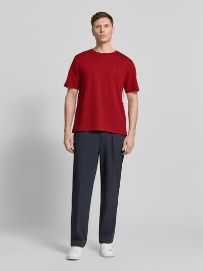 Männermodel trägt Relaxed Fit T-Shirt aus reiner Baumwolle von Tommy Hilfiger in Uni-Rot, Logo-Stitching, kurzarm, Ganzkörperansicht von vorne.