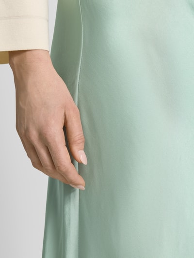 Frauenmodel trägt Midirock in schimmerndem Design von comma, mintgrün, glatte Textur, Material-Mix mit Viskose, Nahaufnahme Oberkörper.