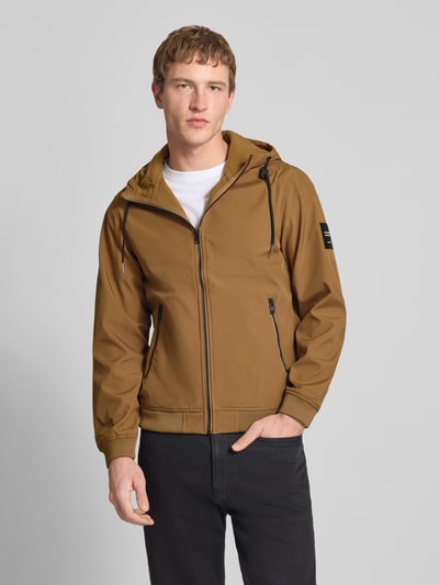 Mannelijk model draagt Softshelljacke mit Reißverschlusstaschen van Jack & Jones in regular fit, bruine kleur, met capuchon en ritszakken, frontale volledige lichaamsweergave.