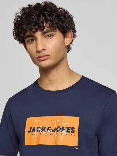 Männermodel trägt Regular Fit T-Shirt aus reiner Baumwolle Modell 'COLE' von Jack & Jones mit Label-Print, Nahaufnahme Oberkörper.