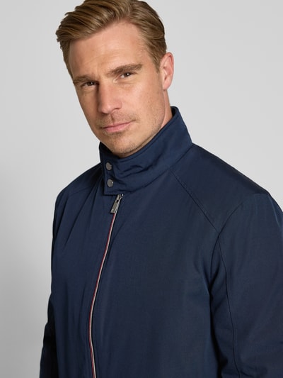 Männermodel trägt Regular Fit Jacke mit Stehkragen von Christian Berg Men in Dunkelblau, Reißverschluss, Nahaufnahme Oberkörper, Kontext: Eingrifftaschen, elastische Abschlüsse, Rückenlänge 69 cm, Schulterbreite 49 cm, Brustweite 55 cm, Ärmellänge 67 cm.