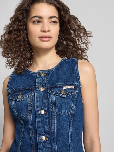 Vrouwenmodel draagt Regular Fit Minikleid in Denim-Optik mit Logo-Patch van Calvin Klein Jeans van puur katoen, mouwloos met ronde hals, borst- en steekzakken, blauwe denim look, logo-patch, detailopname bovenlichaam.