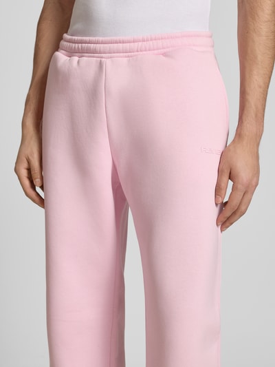 Männermodel trägt Sweatpants mit elastischem Bund von REVIEW in Rosa, Relaxed-Fit, Baumwoll-Anteil, Gesäßtasche, Nahaufnahme Oberschenkel.