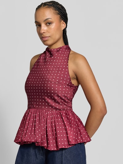 Frauenmodel trägt Slim Fit Bluse mit Peplum-Saum von ROTATE aus bordeauxfarbenem Satin mit floralem Allover-Print, ärmellos, Nahaufnahme Oberkörper.