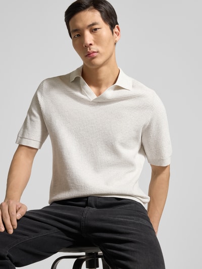 Männermodel trägt Regular Fit Poloshirt aus reiner Baumwolle von Tom Tailor in Strickoptik, V-Ausschnitt, kurzarm, Nahaufnahme Oberkörper.