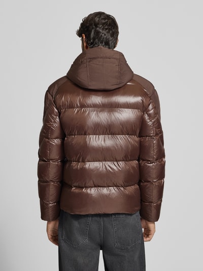 Męski model nosi pikowaną kurtkę z kapturem Steppjacke mit Zweiwege-Reißverschluss Modell 'KIERNAN' od Blauer USA w brązowym kolorze, krój regular fit, label-detail, długość tyłu 67 cm, szerokość ramion 49 cm, szerokość w rozmiarze M 59 cm, długość rękawa 65 cm, pełny widok tyłu.