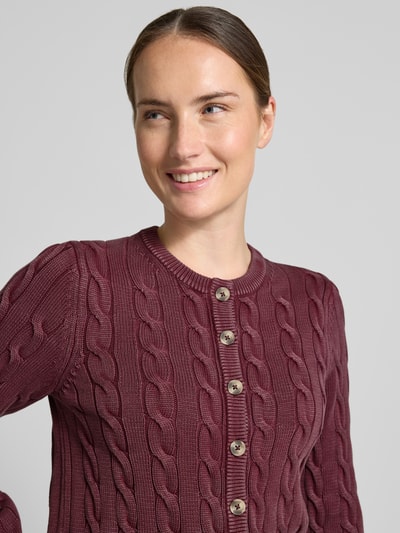 Frauenmodel trägt Relaxed Fit Strickjacke aus reiner Baumwolle von Jake*s Casual in Dunkelrot mit Zopfmuster und Knöpfen, Nahaufnahme Oberkörper.