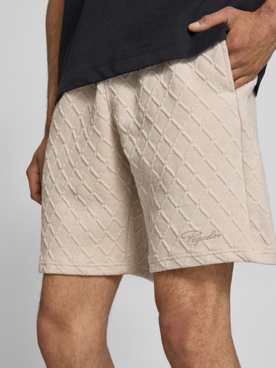 Männermodel trägt Relaxed Fit Shorts mit Strukturmuster Modell 'Jovren' von Pegador, Beige, Elastischer-Material-Mix, Nahaufnahme Oberschenkel, Herren Shorts, Bundweite 39 cm, Innenbeinlänge 24 cm, Größe M.