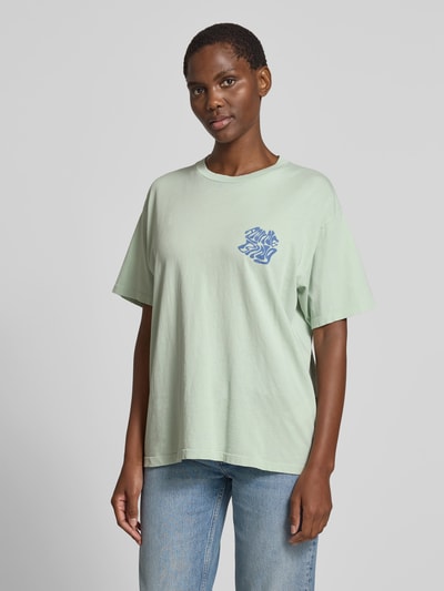 Frauenmodel trägt Oversized T-Shirt mit Logo-Print von Anine Bing aus reiner Baumwolle in Mintgrün, Rundhalsausschnitt, Kurzärmelig, Oversized-Fit, Rückenlänge 62 cm bei Größe S, Ganzkörperansicht von vorne.