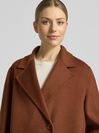 Vrouwenmodel draagt lange jas van katoenmix Model 'RYTON' van DRYKORN in regular fit met reverskraag en knoopsluiting, nahaufnahme bovenlichaam.