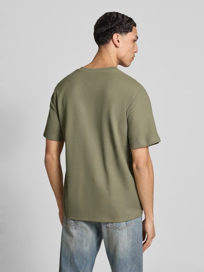 Männermodel trägt T-shirt met ronde hals model 'AUSTIN' van Jack & Jones, elastische materiaalmix met katoenmix, recht model, ruglengte maat M 68 cm, groentinten, gladde textuur, geheel effen, jeans, Ganzkörperansicht Rückansicht