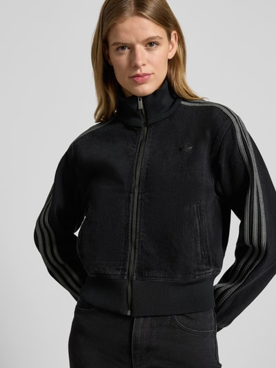 Frauenmodel trägt Jacke mit Reißverschluss von adidas Originals in Schwarz, Regular-Fit, Cropped, Stehkragen, Label-Stitching, Eingrifftaschen, Gerippte-Abschlüsse, Ganzkörperansicht von vorne.