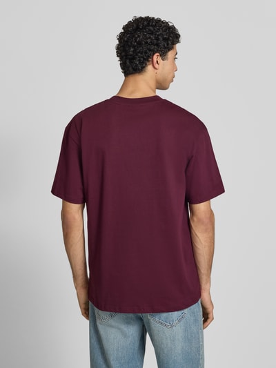 Männermodel trägt Oversized Fit Herren T-Shirt mit Logo-Print Modell 'Heritage' von KARL KANI, Reine Baumwolle, Rückenlänge 73 cm, Ganzkörperansicht Rückansicht