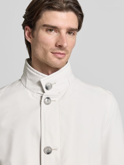 Männermodel trägt Regular Fit Mantel mit Stehkragen Modell 'FYNN' van Strellson in uni crème, twill textuur, Nahaufnahme Oberkörper.