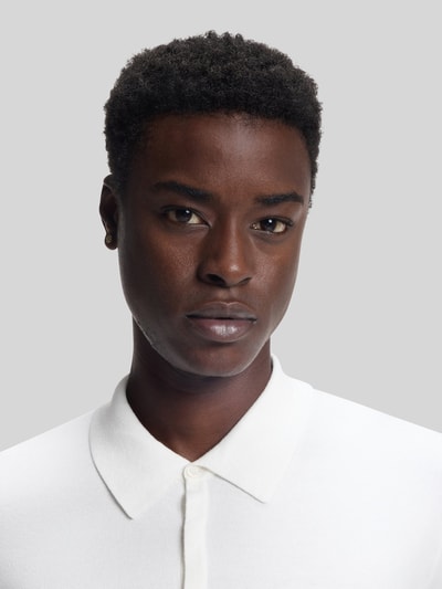 Männermodel trägt Slim Fit Strick-Poloshirt aus Viskose-Mix Modell 'SAN PIPPO-CV' von HUGO, unifarben weiß, Nahaufnahme Oberkörper.