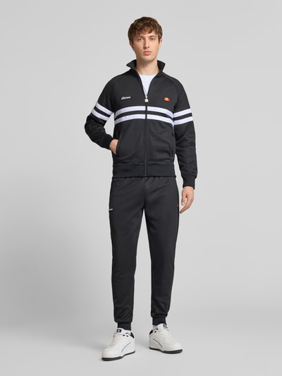 Męski model nosi Sweatpants mit elastischem Bund Modell 'BERTONI' von Ellesse, mieszanka bawełny, krój regular fit, detal z logo, kolor czarny, długość wewnętrzna nogawki w rozmiarze M: 76 cm, ganzkörperansicht von vorne