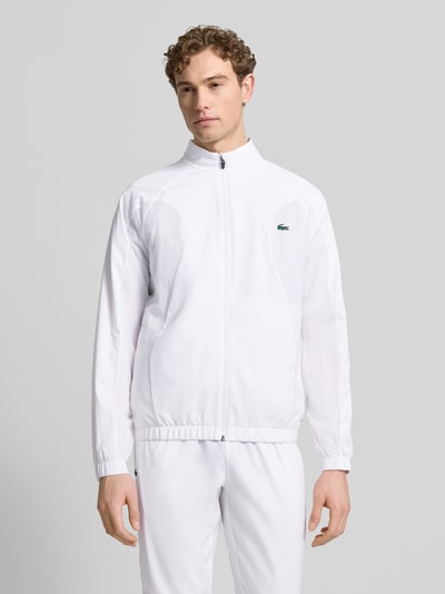 Männermodel trägt Regular Fit Trainingsanzug mit Logo-Detail von Lacoste Sport in Weiß, unifarben, elastische Abschlüsse, Ganzkörperansicht von vorne.