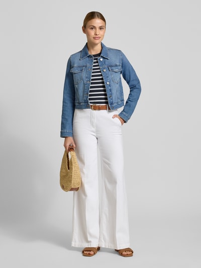 Frauenmodel trägt Jeansjacke mit Brusttaschen Modell 'NEWVICKY' von Mango, Baumwoll-Elasthan-Mix, hellblau, Ganzkörperansicht von vorne.