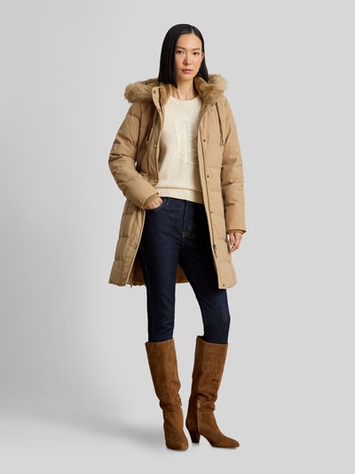 Frauenmodel trägt Regular Fit Daunenmantel mit Besatz aus Webpelz von Lauren Ralph Lauren in Beige, kombiniert mit Jeans und Stiefeln, Ganzkörperansicht von vorne. Damen Daunenmantel von Lauren Ralph Lauren.