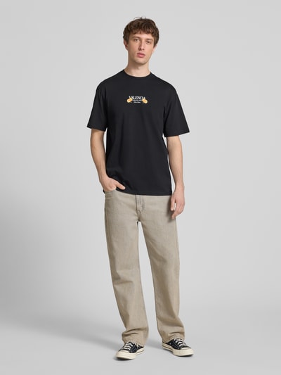 Männermodel trägt Relaxed Fit T-Shirt aus reiner Baumwolle Modell 'TASTY' von Only & Sons in Optik: Unifarben mit Applikation Schriftzug-Print, Passform: Relaxed-Fit, Rundhals, Kurzarm, Material: Reine Baumwolle, Ganzkörperansicht von vorne.