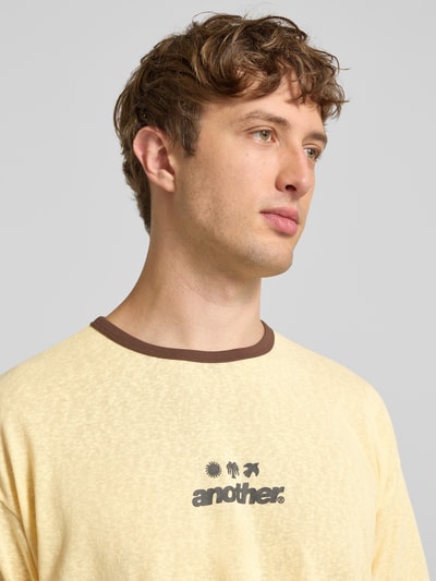Männermodel trägt T-Shirt mit Label-Print und Rundhalsausschnitt von ANOTHER COTTON LAB in Gelb, Reine Baumwolle, Relaxed-Fit, Nahaufnahme Oberkörper.