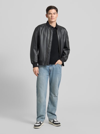 Męski model nosi Regular Fit Poloshirt mit Label-Stitching od Gant, czarny, bawełna, kołnierzyk polo, frontalny widok całej sylwetki.