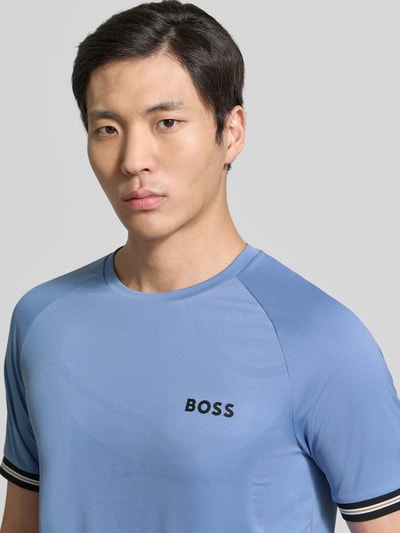 Männermodel trägt Regular Fit T-Shirt mit Label Print Modell 'TOC SERVE 2' von BOSS Green in Hellblau mit Kontraststreifen, Nahaufnahme Oberkörper