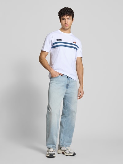 Männermodel trägt Herren T-Shirt mit Label-Stitchings Modell 'VENIRE' von Ellesse in Weiß, Reine Baumwolle, Regular-Fit, Ganzkörperansicht von vorne.
